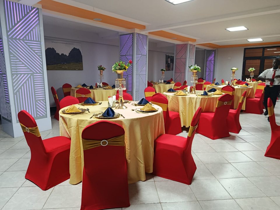 Round tables dressed in gold with red chair covers in the ballroom
