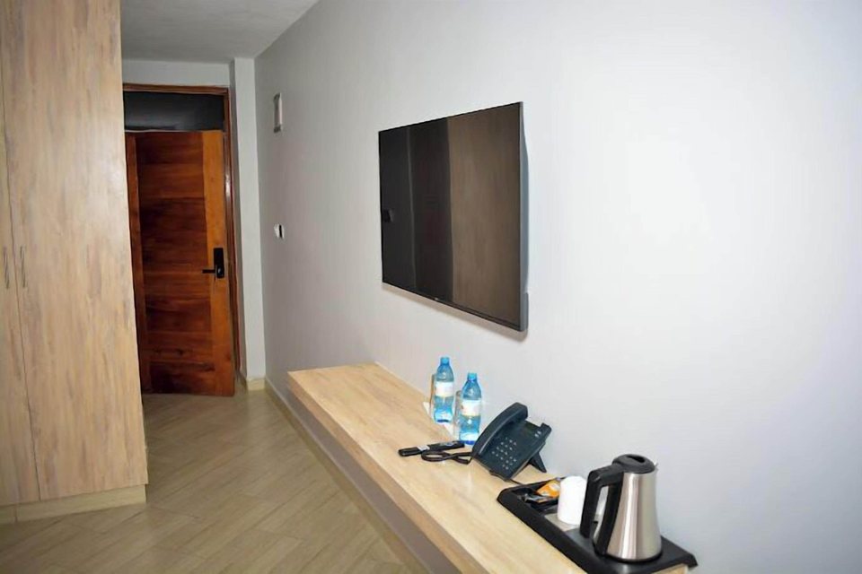 A desk with a flat-screen TV, telephone and kettle
