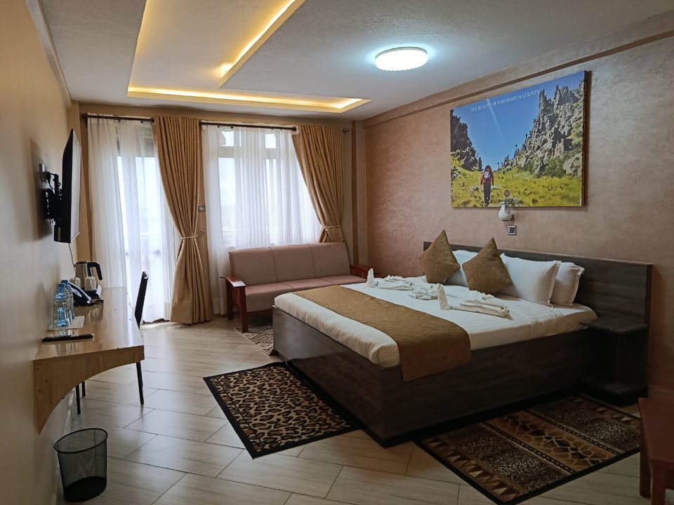 A suite with a sofa, desk and a painting of the Nyandarua hills