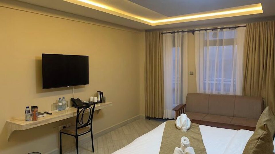 A room with desk, sofa and TV